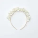 Diadema para el cabello color blanco, decorada con flores de tela en la parte superior.