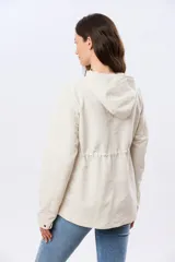 Campera liviana con capucha, de corte clásico, color beige, con bolsillos laterales con solapa y cierre frontal.