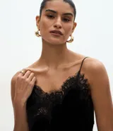 Vestido corto de terciopelo negro, estilo slip dress, con escote corazón, breteles finos y detalles de encaje en el escote y en el ruedo asimétrico con terminación en punta lateral.