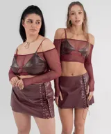 Conjunto de top y minifalda color borgoña. El top es strapless con mangas largas de tul y corpiño de cuero sintético. La minifalda es de cuero sintético con cordones laterales.