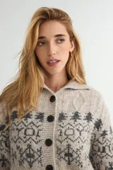 Saco de punto con cuello tipo polo, cierre frontal de botones oscuros y diseño de estampado jacquard en tonos grises y beige. Presenta mangas largas con puños acanalados y textura suave.