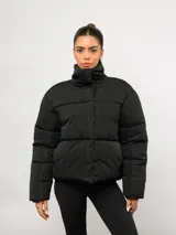 Campera puffer corta Umbro de color negro, con cuello alto, cierre frontal y bolsillos laterales. Presenta un diseño acolchado y logo de la marca bordado en el pecho.