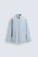 Camisa de corte regular fit confeccionada en tejido de algodón con estampado de microcuadros. Presenta cuello abotonado, manga larga con puños abotonados y cierre frontal con botones.