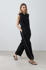 Mono negro de lino con corte recto, cuello camisero, sin mangas y vivo blanco en contraste en cuello, sisas y laterales.