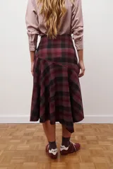 Falda midi de corte irregular con diseño a cuadros en tonos marrones, negros y beige. Presenta una silueta acampanada con caída fluida.