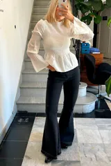 Pantalón de jean negro con corte oxford, de tiro medio y botamanga acampanada con ruedo deshilachado.