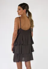 Vestido corto verde militar con diseño de solera con tirantes finos, escote recto y múltiples volantes horizontales escalonados.