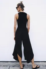 Mono largo negro con cuerpo de tejido ajustado sin mangas y cuello redondo, combinado con pantalón ancho de tejido fluido y satinado con diseño abullonado y bajo asimétrico. Cierre trasero con cremallera oculta.