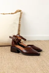 Zapatos de cuero color chocolate con diseño de punta cuadrada, taco bloque bajo y tira ajustable al tobillo con hebilla metálica.