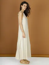 Vestido largo color crema de lurex plisado, con cuello halter y corte recto.