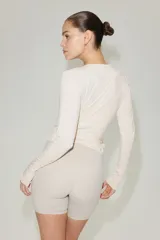 Top deportivo cruzado de modal suave, en color beige claro, con escote en V pronunciado, mangas largas y tiras para anudar en la cintura.