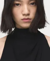 Vestido corto negro sin mangas con cuello alto drapeado y lazo en la parte posterior.