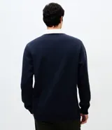 Buzo masculino de algodón con felpa, color beige, con cuello polo blanco contrastante, manga larga y puños acanalados.