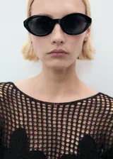 Jersey de punto grueso negro con cuello barco, manga larga y detalles florales bordados en el frente.