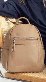 Mochila pequeña de símil cuero color negro, con bolsillo frontal con cierre, asa de mano y correas regulables.