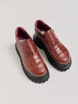 Mocasines color marrón con estampado de cocodrilo y plataforma negra con suela dentada.