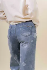 Pantalón de jean de corte recto y relajado, con tiro medio-alto. Presenta un estampado floral sutil en tonos claros sobre la base de denim azul y cuenta con interior forrado para mayor abrigo.