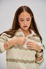 Sweater de punto con cuello alto y cierre frontal, de manga larga. Presenta un patrón de ondas en tonos beige, verde claro y blanco.