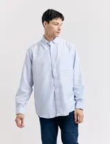 Camisa celeste con pequeños lunares blancos, de manga larga, con cuello abotonado y bolsillo en el pecho.