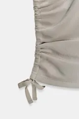 Pantalón capri de tiro medio con efecto lavado, bolsillos delanteros y traseros, y bajo con frunces laterales ajustables mediante cordones.