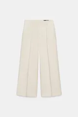 Pantalón cropped de tiro medio con cintura con trabillas, bolsillos laterales y detalle de nervio frontal. Cierre con cremallera, botón y ganchos metálicos.