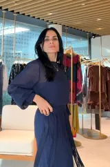Vestido midi de color azul marino, con mangas largas ligeramente abullonadas y falda plisada. Presenta un diseño con cintura definida y un detalle de hebilla lateral.