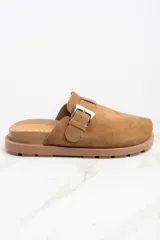 Zueco de cuero color marrón claro, con hebilla metálica plateada ajustable y suela plana con ranuras.