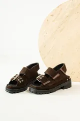 Sandalias negras de cuero con diseño de plataforma dentada, tiras ajustables con hebillas metálicas y detalle de tachas plateadas en el lateral de la suela.