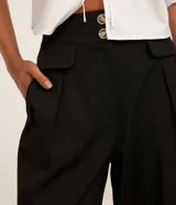 Pantalón de vestir negro, de corte wide leg, con cintura alta, bolsillos laterales y traseros.