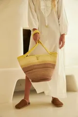 Bolso de mano tipo tote, confeccionado en soga de algodón con diseño a rayas horizontales en degradé de color marrón y beige. Asas de hombro amarillas y cierre con broche de bronce.