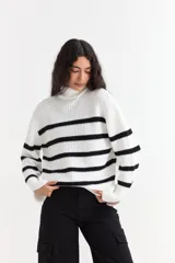 Sweater de punto con cuello alto, diseño de rayas horizontales en color blanco y negro, mangas largas y corte holgado.