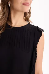 Blusa de viscosa negra sin mangas, con diseño fluido, cuello redondo y detalles de tablas verticales en el pecho con terminaciones de encaje en las sisas.