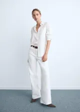 Jeans wide leg blancos de tiro alto con diseño de cinco bolsillos, trabillas para cinturón y bajo deshilachado. Cierre frontal con cremallera y botón.