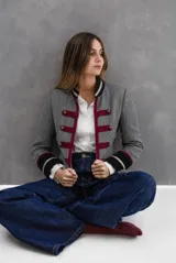 Chaqueta estilo napoleónico confeccionada en tela de paño tweed con patrón de espiga. Presenta cuello y puños en terciopelo azul con detalles de cintas doradas, pasamanería en color bordó y botones metálicos empavonados.