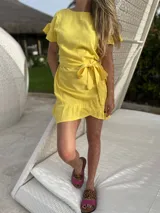 Vestido corto blanco de lino con corte evasé, mangas cortas con volados y cinto del mismo material.