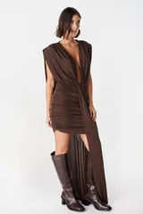 Vestido corto de diseño asimétrico en color verde oliva, con escote profundo en V, drapeado frontal y una caída lateral larga que llega hasta el suelo. Sin mangas y con ajuste entallado en la falda.