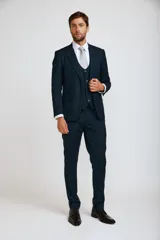 Traje de tres piezas compuesto por saco, chaleco y pantalón de corte slim fit en color azul oscuro. El saco presenta solapas clásicas y cierre de dos botones, el chaleco cuenta con cierre frontal de botones y el pantalón es de corte recto y entallado.