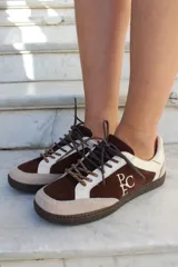 Championes de cuero vacuno en combinación de azul y gris, con suela de goma y cordones. Presenta detalle de bordado con las iniciales de la marca en el lateral externo.