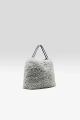 Cartera de hombro gris con textura peluda y correa larga ajustable.