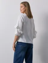 Blusa de gasa estampada con flores azules y violetas sobre fondo blanco, de manga 3/4 con volados.