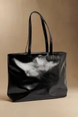 Bolso tipo tote de cuero sintético negro, con doble asa superior para hombro y diseño estructurado.