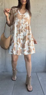Vestido corto color beige con estampado de hojas marrones, escote en V, botones frontales y volados en ruedo.