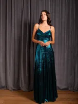 Vestido largo metalizado color negro, con tirantes finos, escote en V, falda plisada y espalda abierta con nudo.