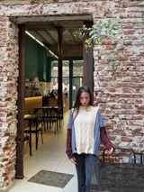 Sweater de punto con diseño de ochos y estilo patchwork, combinando paneles en colores terracota, marrón y beige. Presenta cuello redondo, mangas largas y costuras decorativas a la vista.