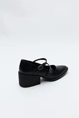 Zueco estilo Mary Jane color negro charol, con doble tira y hebillas metálicas. Presenta punta cuadrada y taco ancho de altura media.