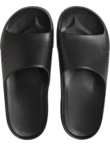 Ojotas tipo slide negras, con tira ancha que presenta el logo 'CK' en relieve en el lateral. La plantilla es contorneada con textura acanalada para mayor agarre.