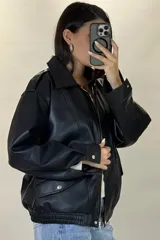 Chaqueta de ecocuero color marrón, de corte oversize, con cuello clásico, cierre frontal metálico, bolsillos laterales con solapa y puños con broches a presión.