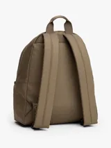 Mochila de diseño redondeado en color marrón, confeccionada en poliéster texturizado. Cuenta con un compartimento principal con cierre, un bolsillo exterior con cremallera y un bolsillo interior de malla. Incluye asa superior y correas ajustables y acolchadas. Presenta un parche tejido con el logo de Tommy Jeans en la parte delantera.