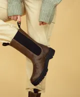 Bota de caña media color chocolate oscuro, realizada en cuero encerado. Con elástico italiano en la caña de ambos lados y fondo artesanal de suela color negro. El interior está forrado en forrería vacuna.