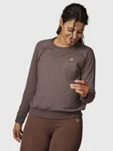 Polera de manga larga en color marrón chocolate con efecto melange. Presenta cuello redondo, mangas raglán, puños elásticos y cintura con ajuste elástico. Incluye un pequeño logo bordado en el pecho.
